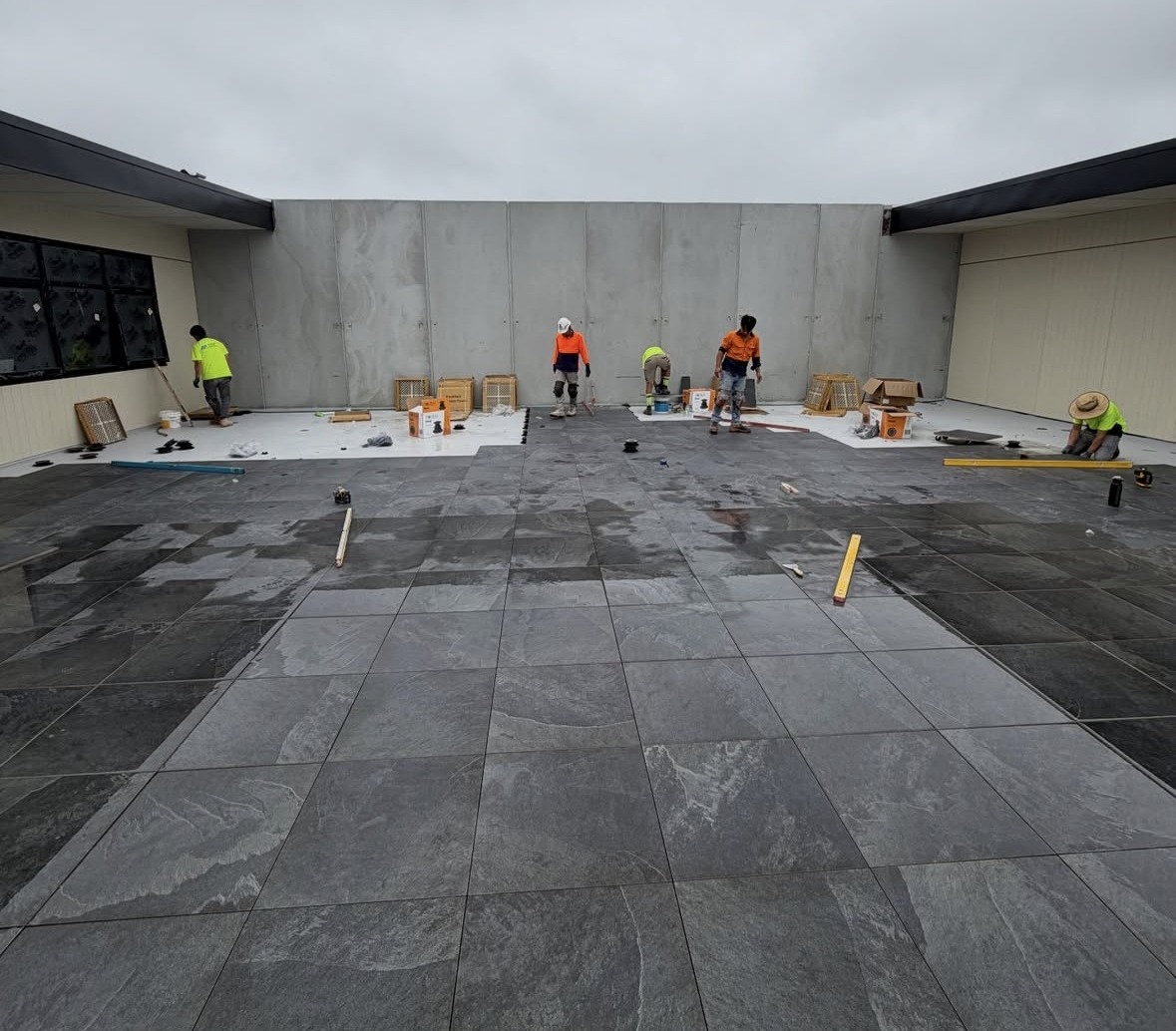 Crew working across a large external podium paving installation